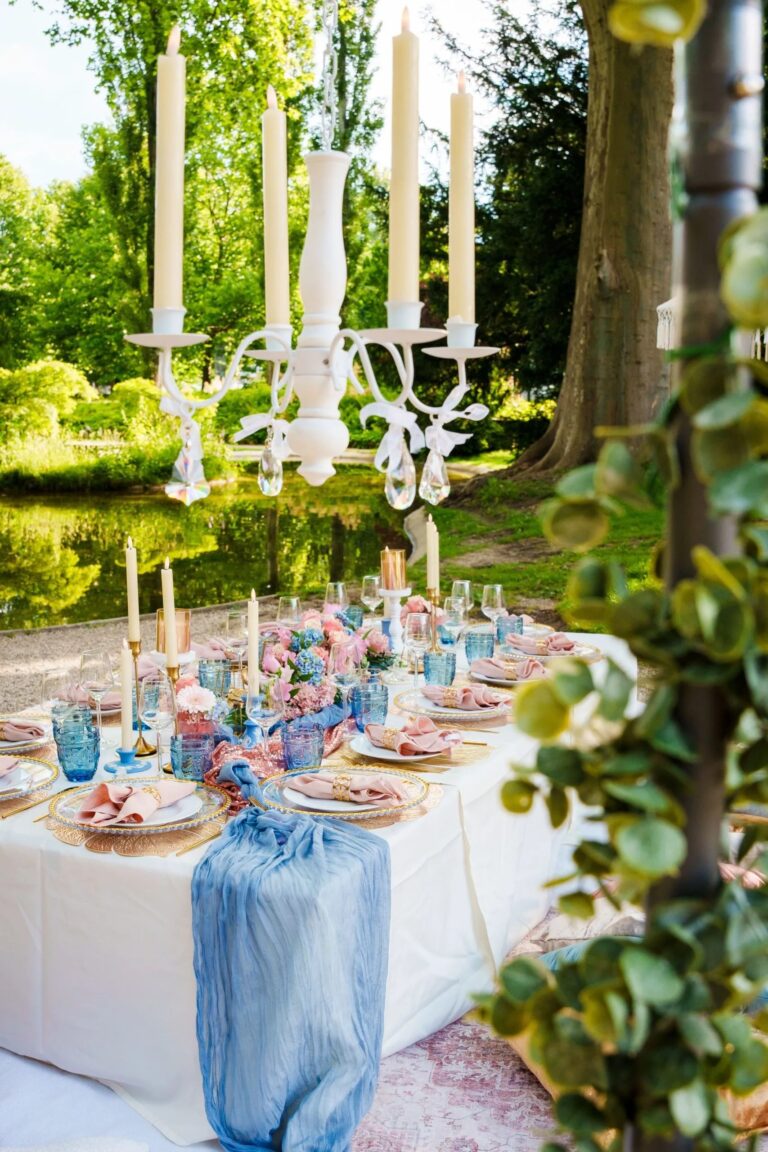 Picnic table with candelabra, blue linen and pink florals in a garden, Vienna Picnics