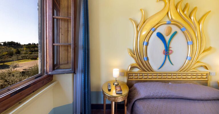 Guest room with painted headboard and window onto the hills, Villa Castiglione