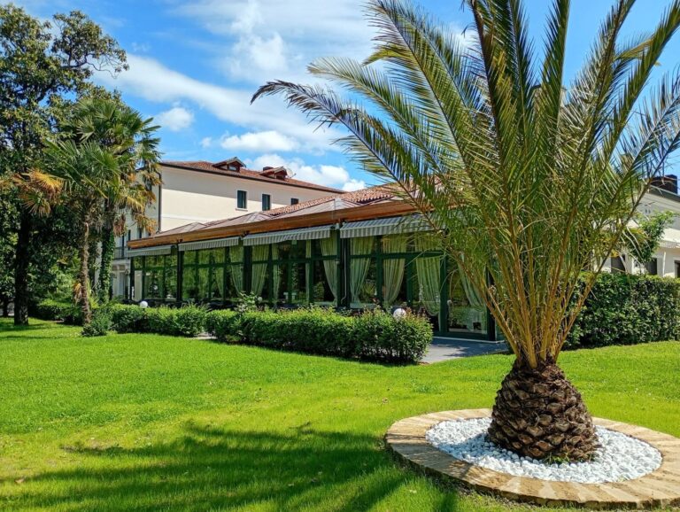 The villa and its summer veranda restaurant from the lawn, a palm and blue Veneto sky above, Villa Pace Park Hotel Bolognese
