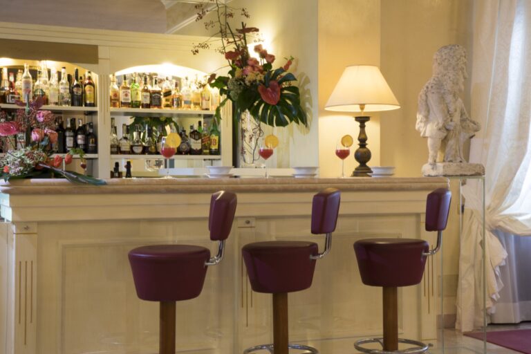 The villa lounge bar, backlit bottles, orchids and violet stools beneath a soft lamp, Villa Pace Park Hotel Bolognese