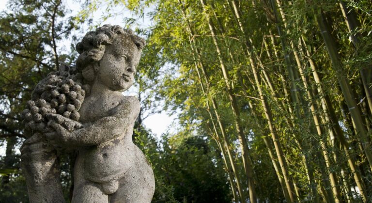 A stone cherub cradling grapes in a grove of bamboo in the park, Villa Pace Park Hotel Bolognese