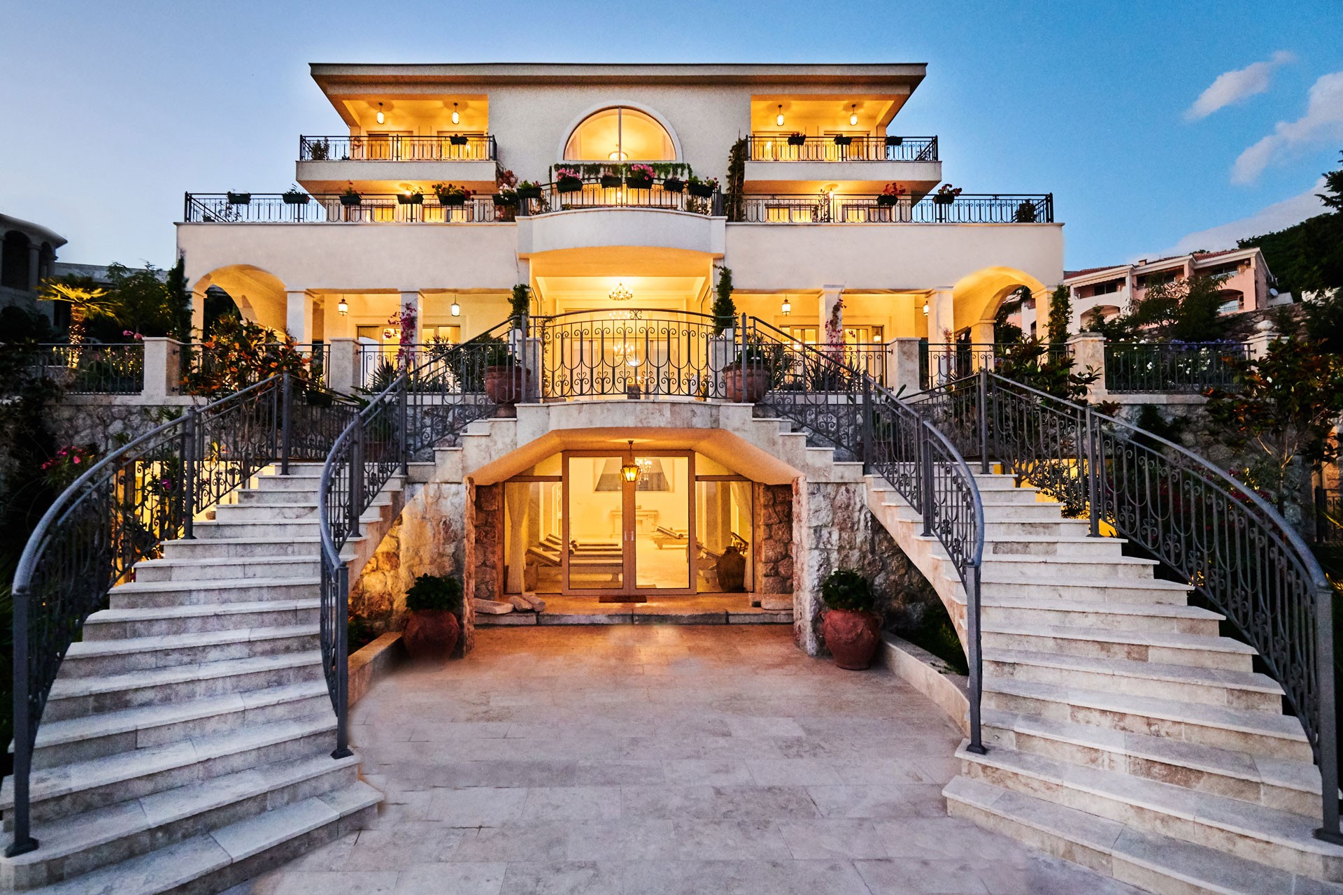 The villa and its curved staircase lit at dusk, Villa Ponta Melagrana