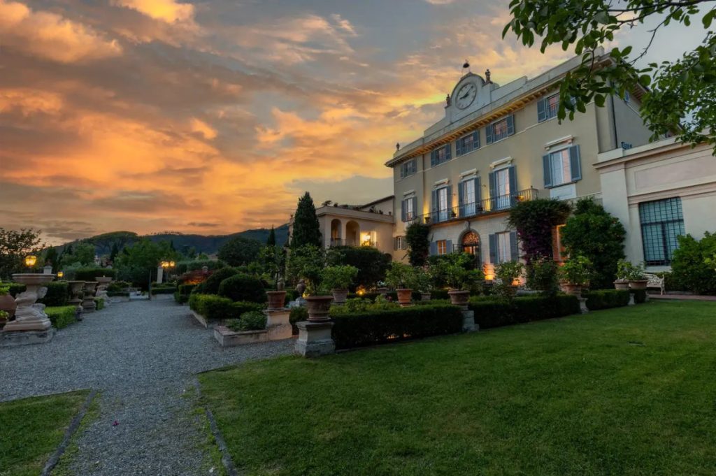 The villa's pale façade and formal garden at sunset