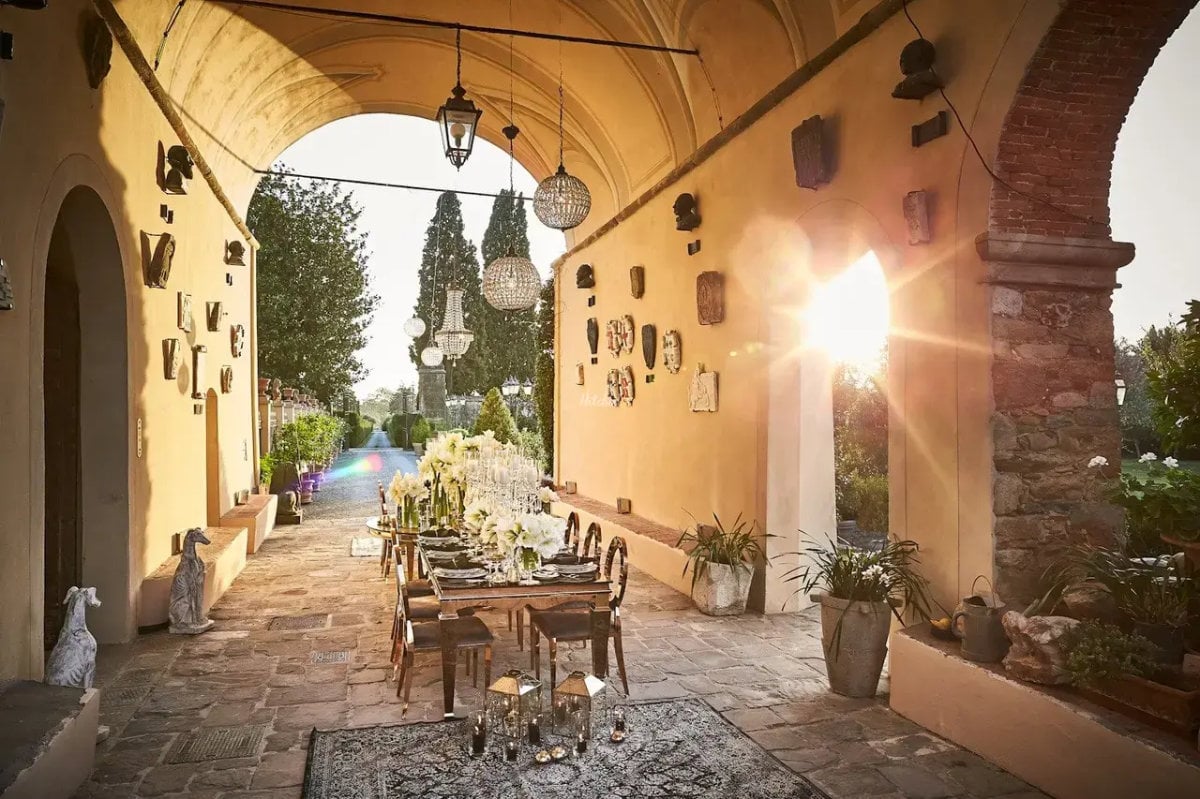 A table laid under a stone loggia with the garden beyond