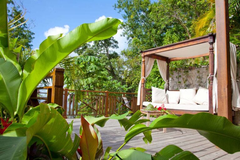 A canopy daybed on a timber deck among tropical planting, Villa Susanna St Lucia
