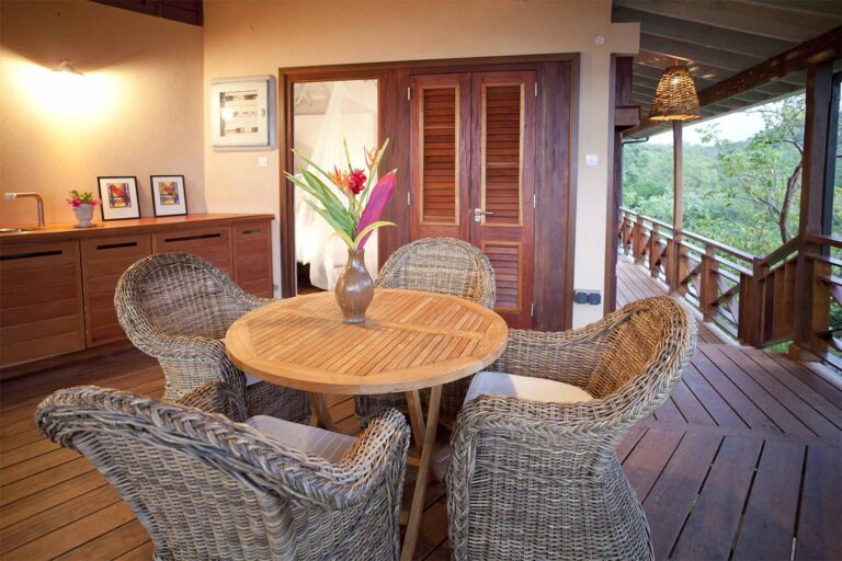 A table and wicker chairs on the veranda beside a bedroom door, Villa Susanna St Lucia