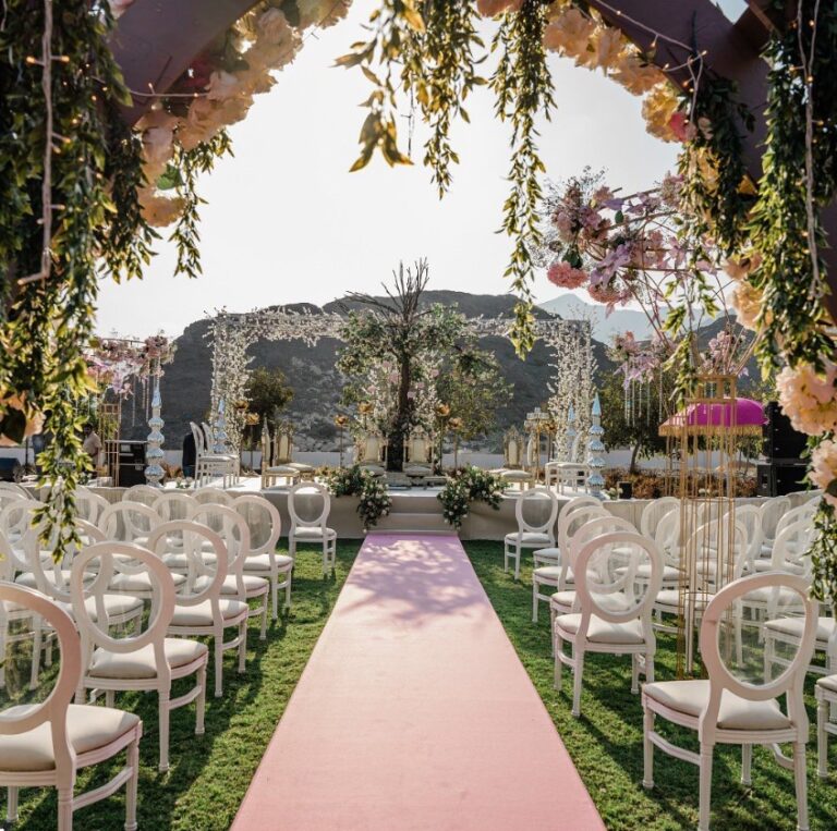 Ceremony seating under hanging greenery and a floral arch, with mountains behind, Vivaah Weddings