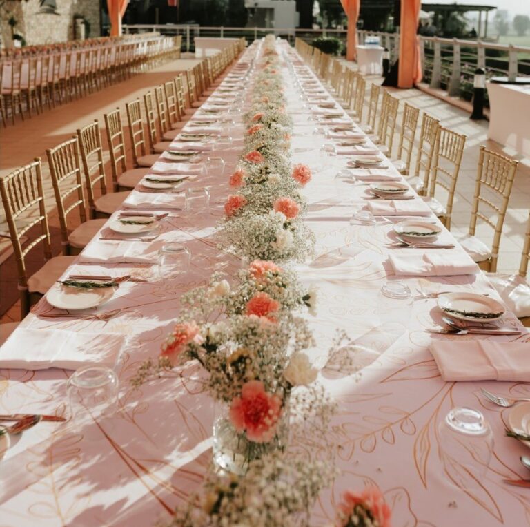 Long guest table dressed with peach and white flowers, Vivaah Weddings