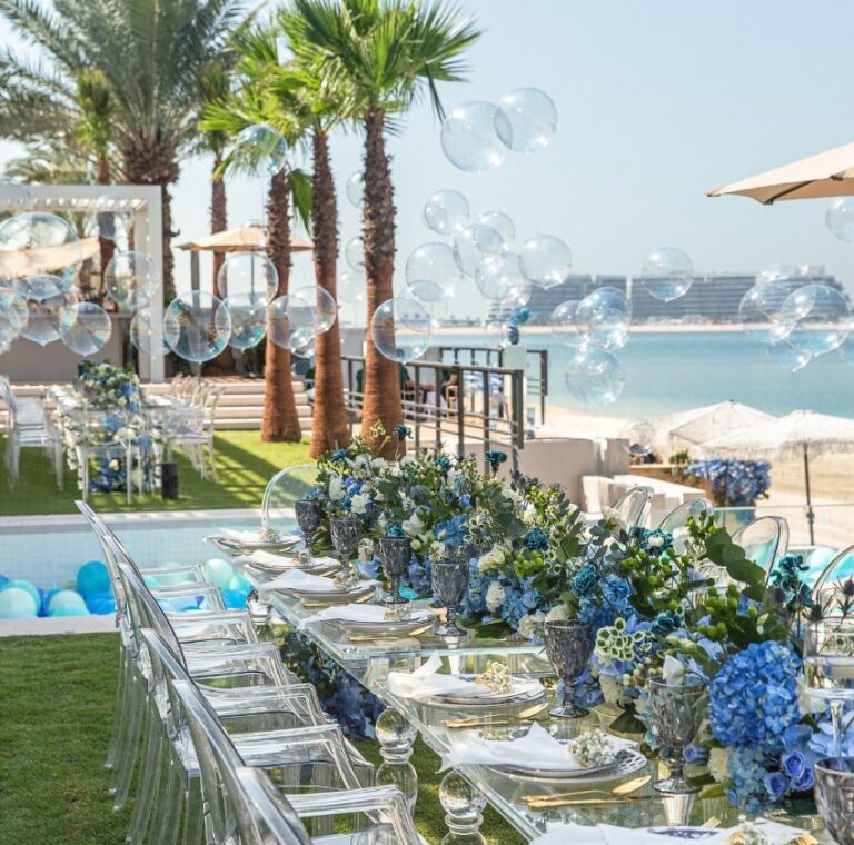 Poolside table set with blue hydrangeas and clear chairs, Vivaah Weddings