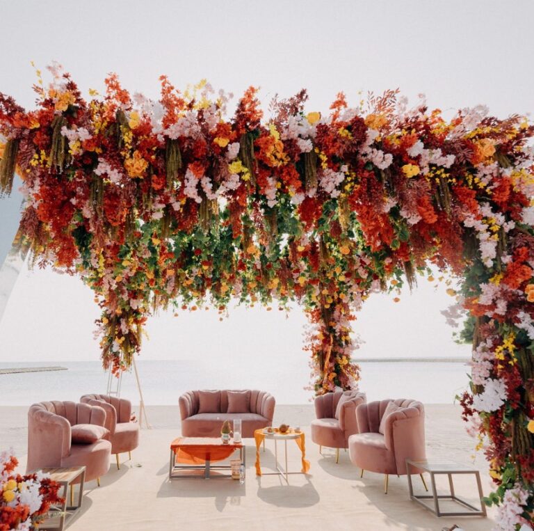 Hanging floral canopy over pink lounge seating on a white beachfront terrace, Vivaah Weddings