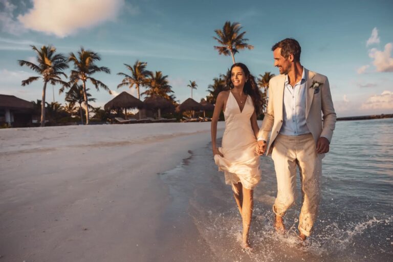 A couple walking along the beach at sunset, Waldorf Astoria Maldives Ithaafushi