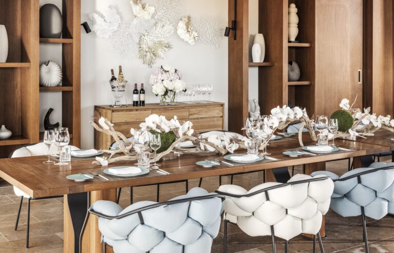 A long dining table set with flowers and white chairs, Waldorf Astoria Maldives Ithaafushi