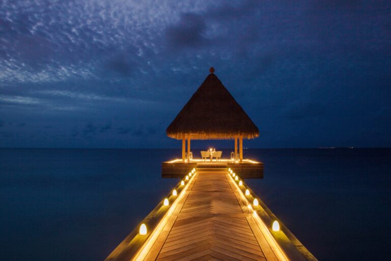 A lit jetty leading to a pavilion over the sea at night, Waldorf Astoria Maldives Ithaafushi