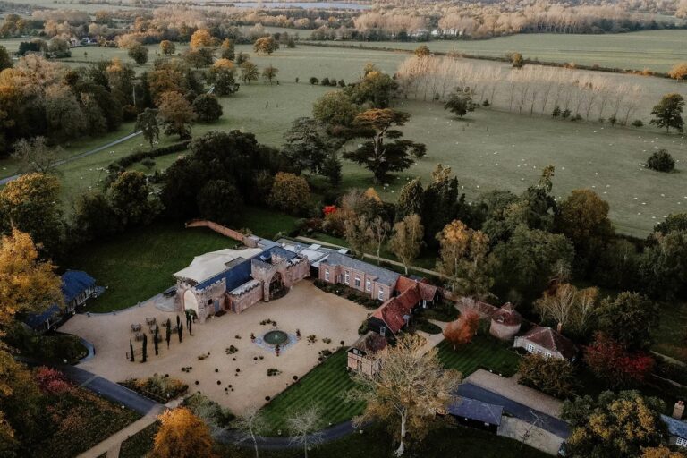 Autumn aerial view of Wasing Park, the courtyard and gardens framed by trees with the estate parkland stretching away, Wasing Park Weddings