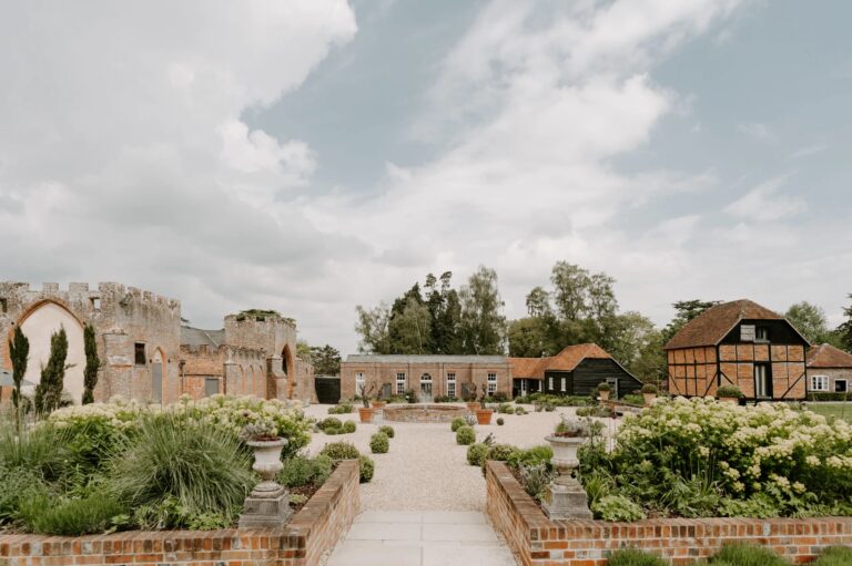 The walled courtyard garden with stone urns and raised brick beds, the Castle Barn to the left and the Granary at the far end, Wasing Park Weddings