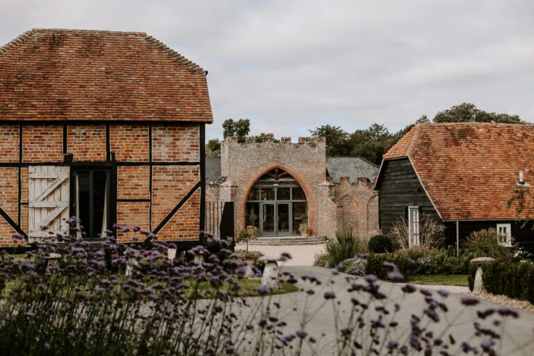 Timber-framed farm buildings either side of the Castle Barn archway, with lavender in the foreground, Wasing Park Weddings