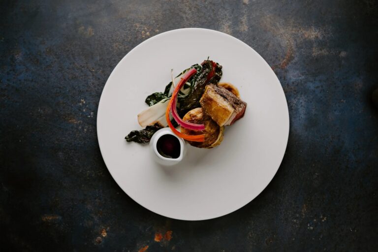 A plated sirloin main course from the estate's Nose to Tail menu, with rainbow chard and a jug of sauce, Wasing Park Weddings