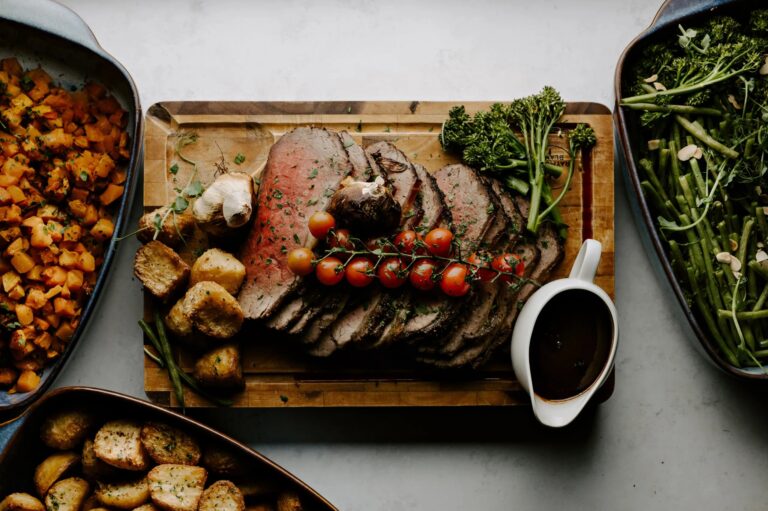 A Farmhouse-style sharing board of carved rare beef with roast potatoes, squash and greens, Wasing Park Weddings