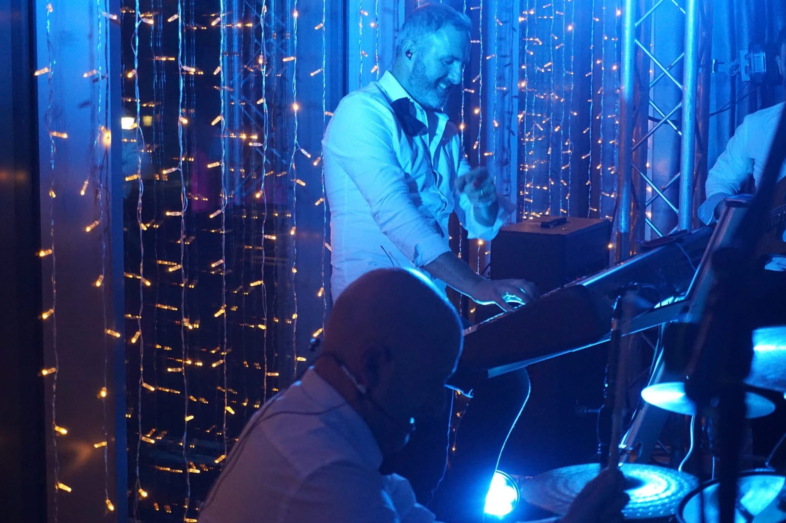 A keyboard player in front of a curtain of fairy lights, Waterfront
