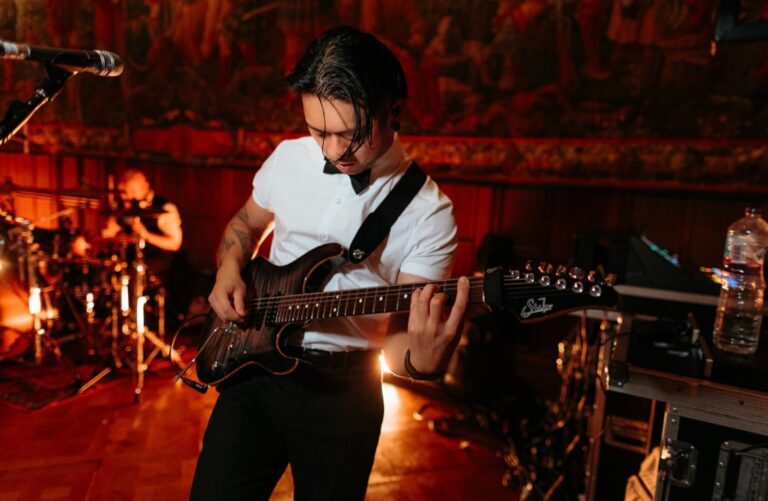 A guitarist playing in warm orange stage light, Waterfront