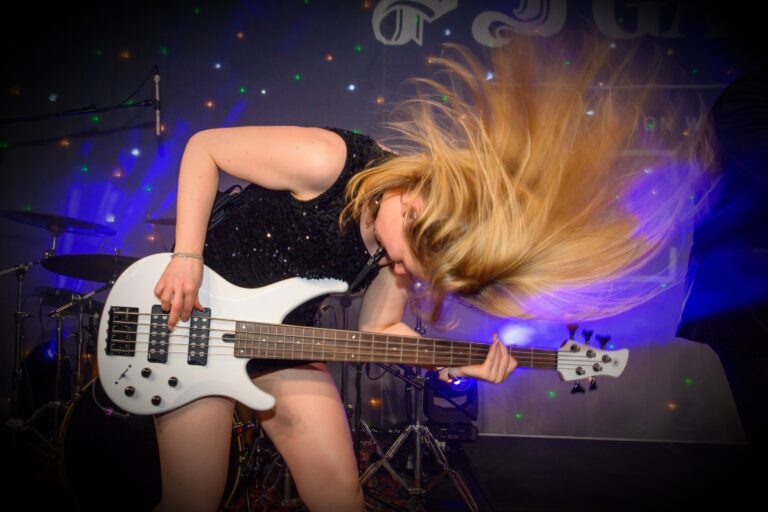A bass guitarist mid-song under blue light, Waterfront