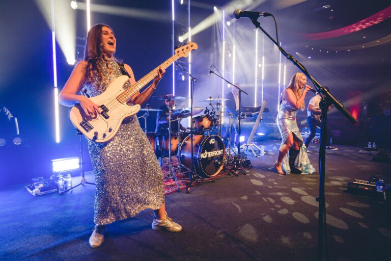 A bass player and a vocalist on stage in blue and white light, Waterfront