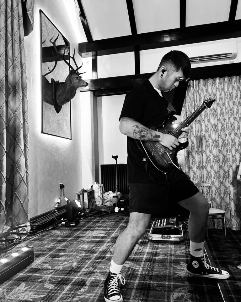 A guitarist in a lodge-style room, in black and white, Waterfront