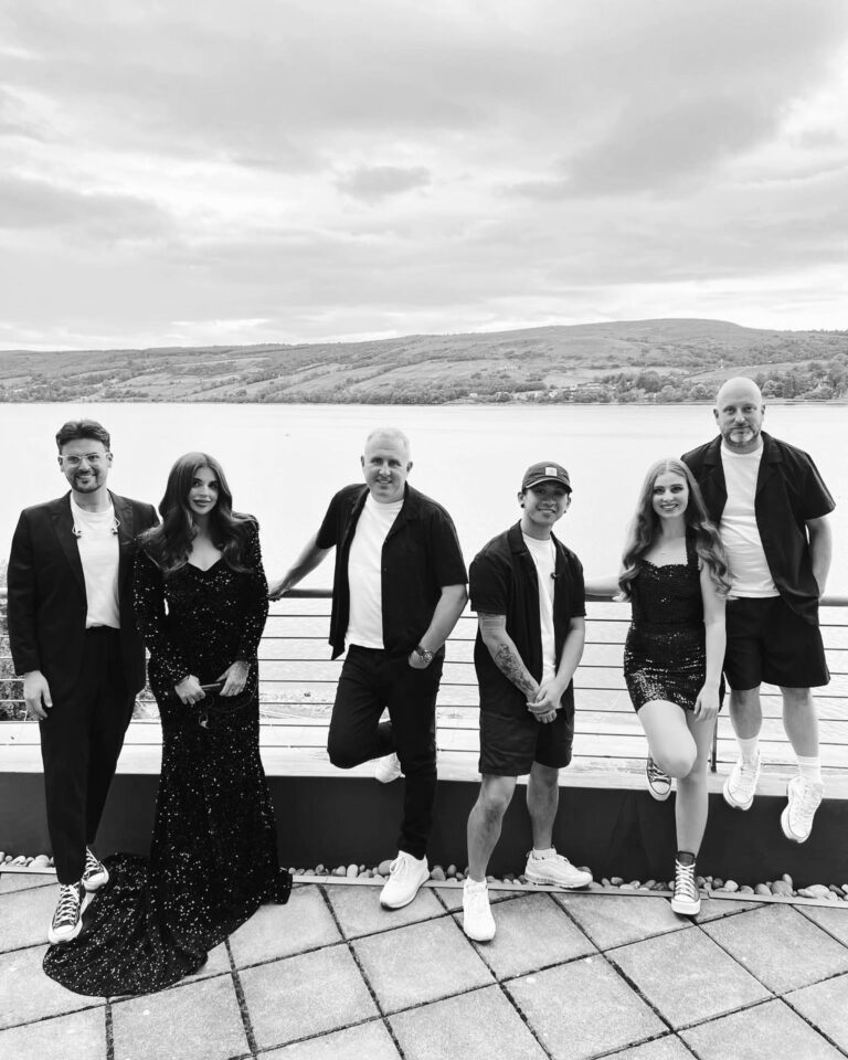 The band standing together by the water, in black and white, Waterfront
