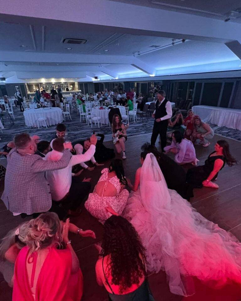 Guests and a bride in a white gown gathered on the dance floor, Waterfront