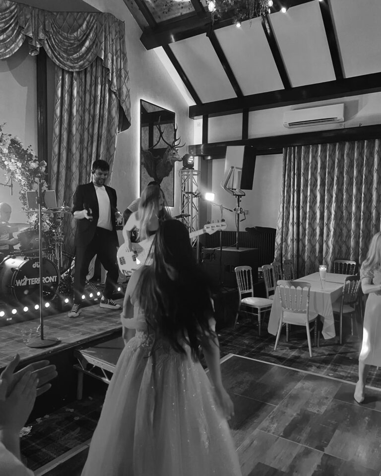 Black and white view of a guest in a ballgown on the dance floor with the band behind, Waterfront
