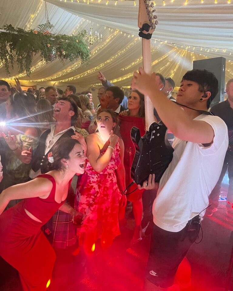 Guests dancing beneath a draped ceiling hung with greenery and fairy lights, Waterfront