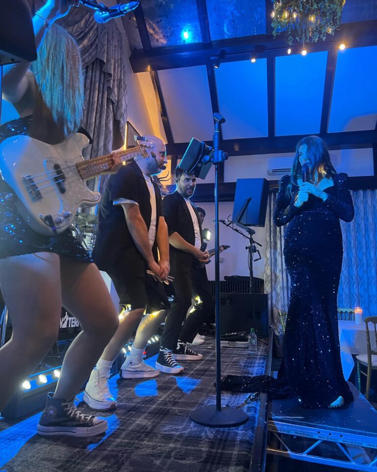 The band performing on a raised platform in front of guests, Waterfront