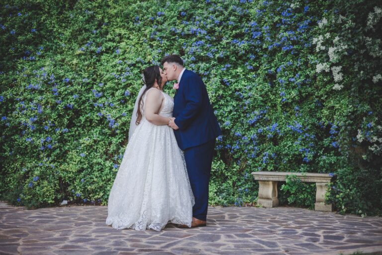 Couple kissing against a wall of blue plumbago, Wed In Malta