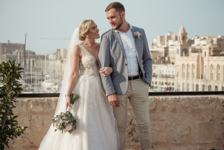 Couple on a terrace with the Three Cities waterfront behind, Wed In Malta
