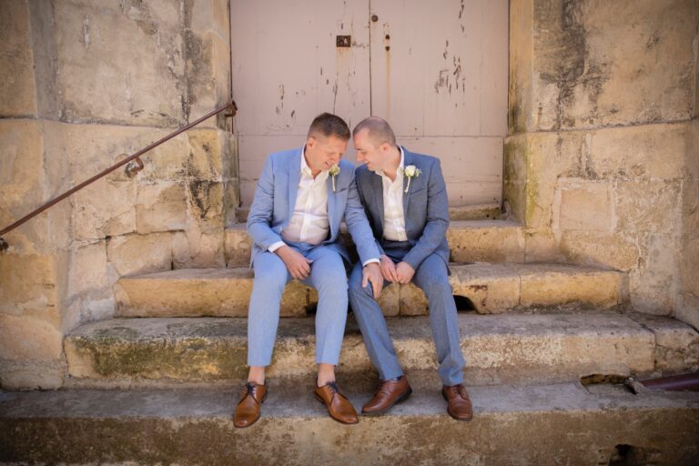 Two grooms seated together on old stone steps, Wed In Malta