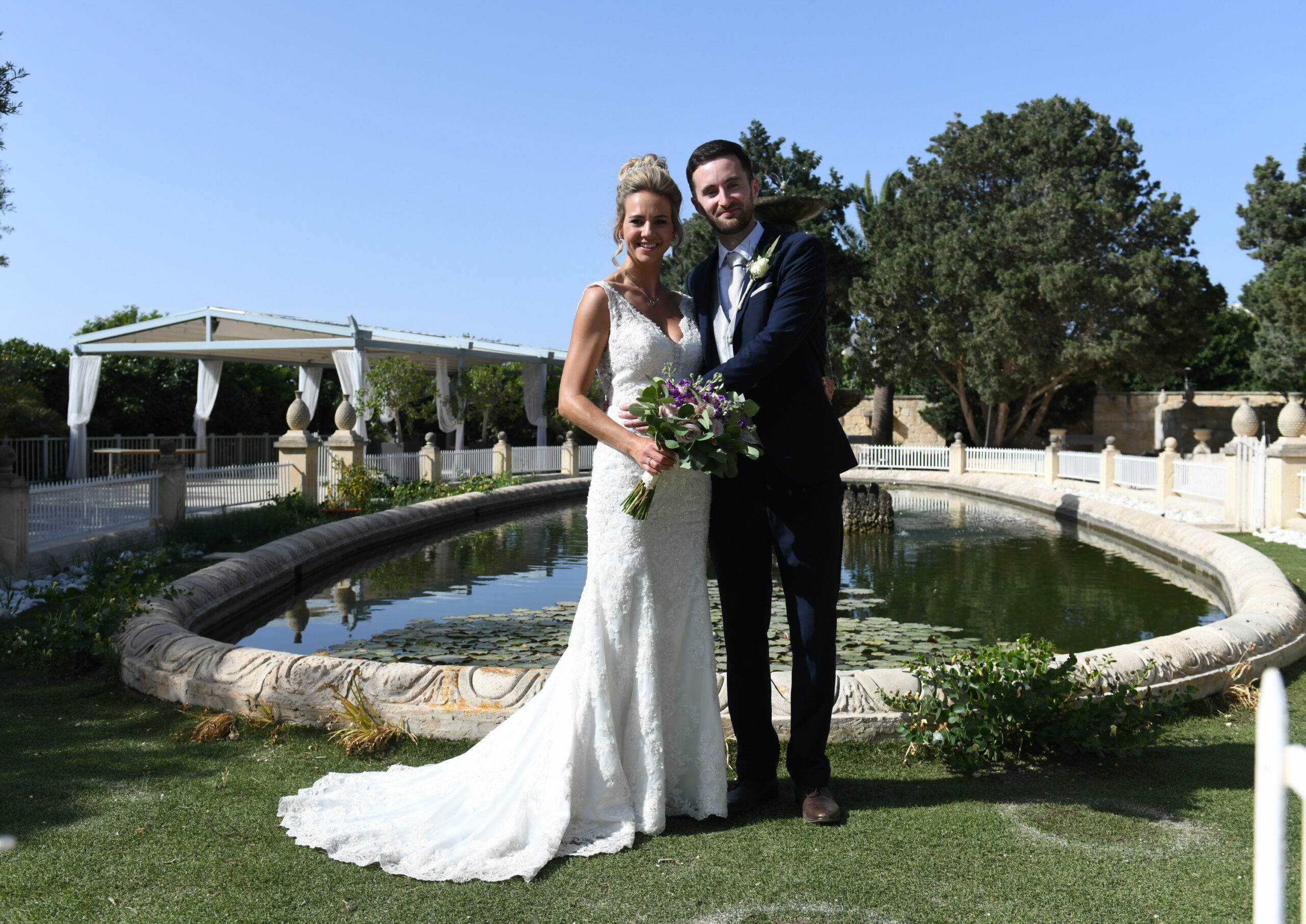 Couple beside a garden pond with a marquee behind, Malta, Wed In Malta