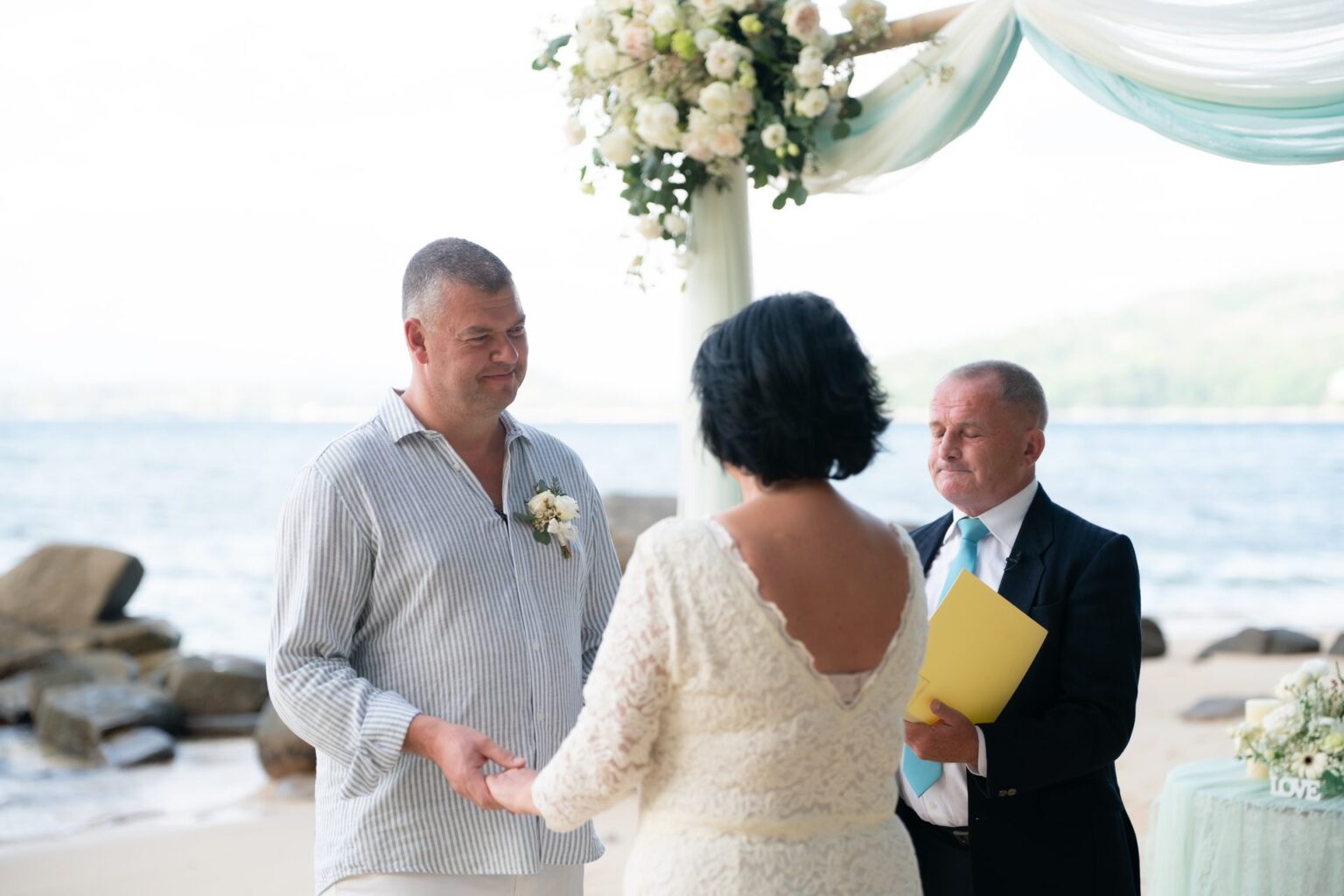 A vow renewal on Hua Beach with a pastel draped arch