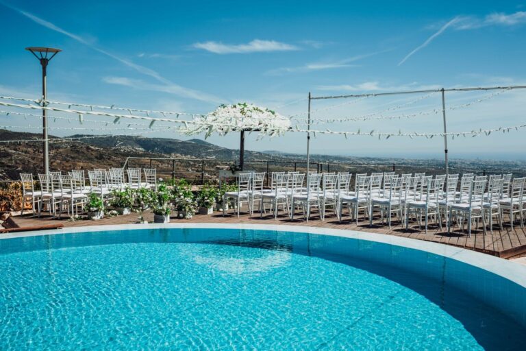 Rows of white chairs beside the pool, set for a ceremony, Wedding Cyprus Villas