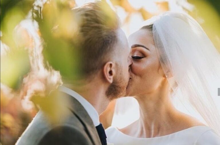 A bride and groom kiss under golden autumn leaves, a cathedral veil catching the light, Wedding Hair And Makeup By Lisa