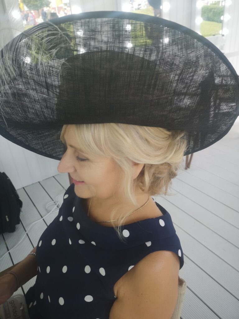 A wide-brimmed black hat with an ostrich feather, styled for the races, Wedding Hair And Makeup By Lisa
