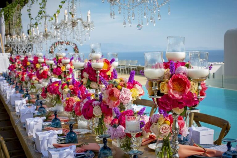 Vivid pink and red table centrepieces on a long table with sea views, Wedding in Greece
