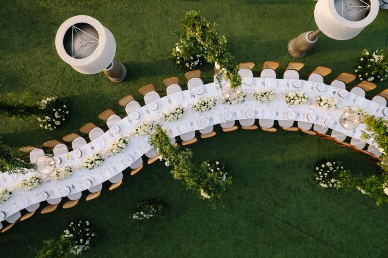 A curving banquet table decorated with greenery seen from above, Wedding in Greece