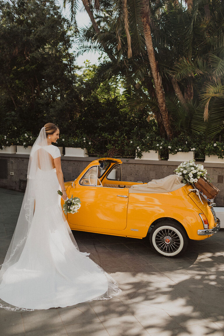 Bride in a long veil beside the yellow Fiat 500 in a shaded lane, Wedding In Yellow Vintage