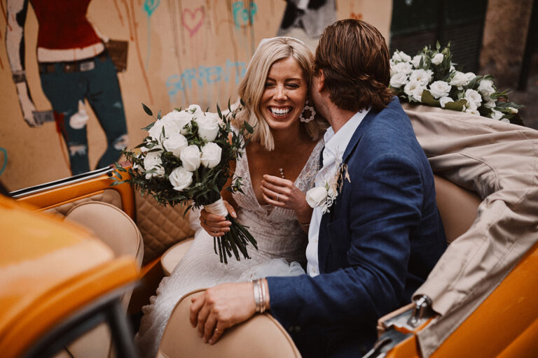 Couple laughing in the back of the yellow Fiat 500 with a white bouquet, Wedding In Yellow Vintage