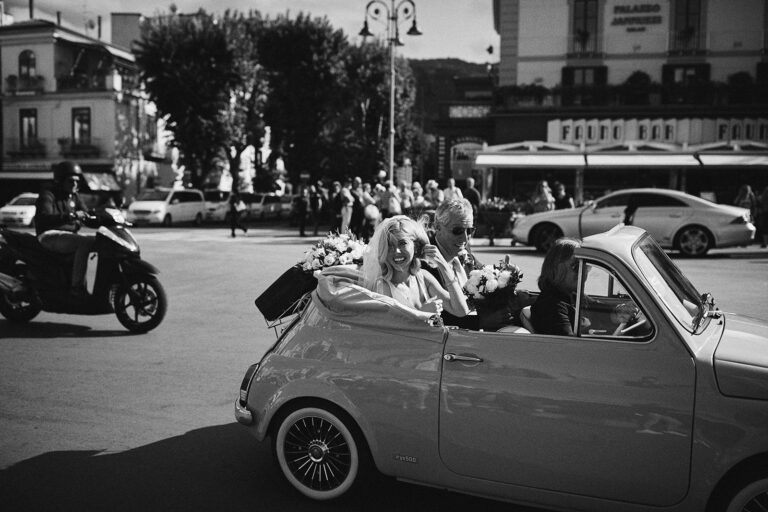 Bride and groom driving through a piazza in the open Fiat 500, black and white, Capri, Wedding In Yellow Vintage