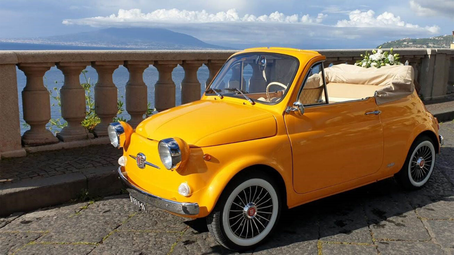 The yellow Fiat 500 on a balustraded terrace above the Bay of Naples