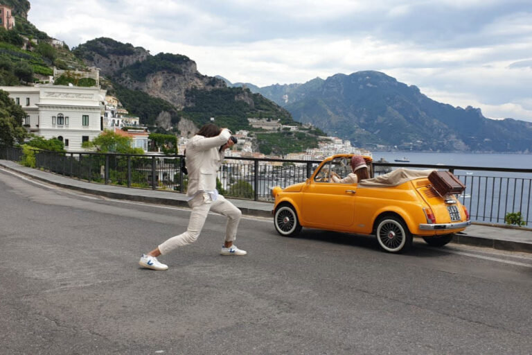 Groom dancing beside the Fiat 500 on the coast road, Amalfi Coast, Wedding In Yellow Vintage
