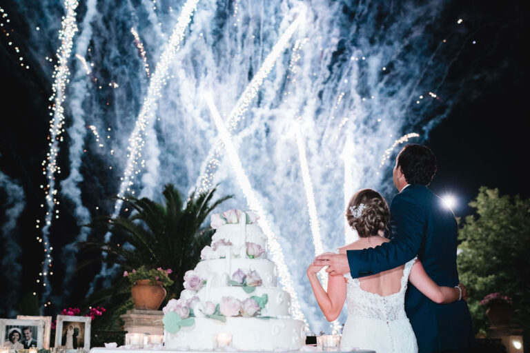 Couple watching fireworks behind a tiered wedding cake, Wedding Sicily