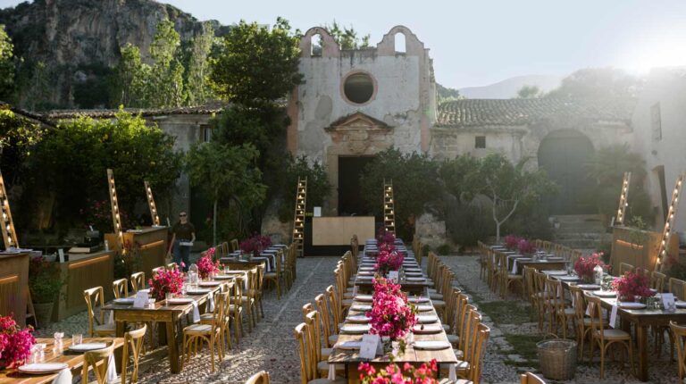 Tables dressed with pink flowers in a stone courtyard, Wedding Sicily