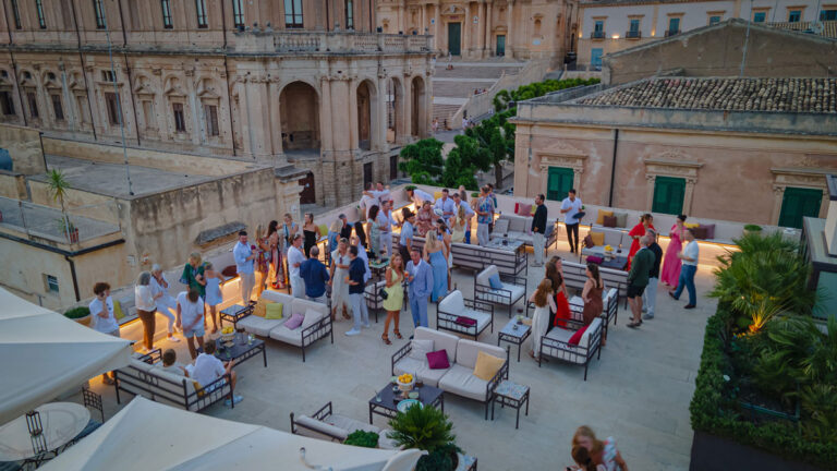 Aerial view of a terrace lounge with guests beside a historic palazzo, Wedding Sicily